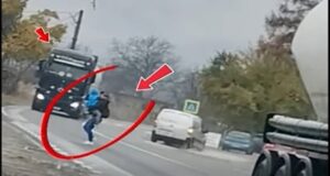 FOTO Mamă surprinsă traversând printre TIR-uri, cu copilul în brațe